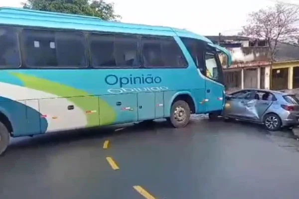 Ônibus azul claro colide com carro cinza em curva de avenida - Metrópoles