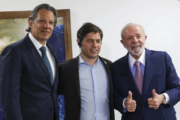 Imagem colorida de Fernando Haddad (esquerda), Axel Kicillof (centro) e o presidente Lula (direita)
