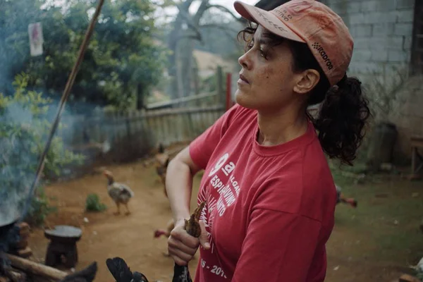 Atriz Maeve Jinkings em cena do filme Carvão, na imagem a personagem Irene segura uma galinha com os pés - Metrópoles