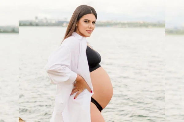Mulher grávida posa para fotos em frente a um lago