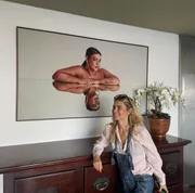 Carolina Dieckmmann posa ao lado de um quadro de Preta Gil, que morreu á 3 meses