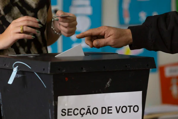 Imagem colorida de pessoa depositando voto durante eleição legislativa em Portugal - Metrópoles