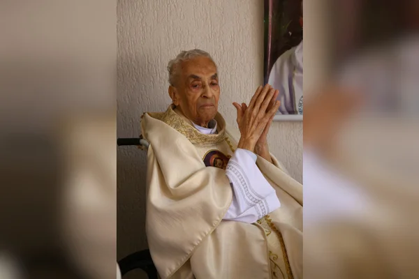 sacerdote sentado com as mãos juntas