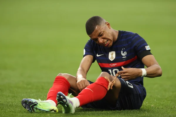 Mbappé sentado no campo