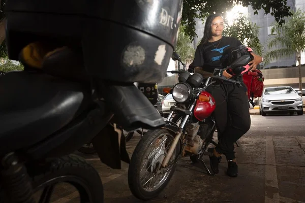 Motogirl Taina Moreira ao lado de sua motocicleta em frente a uns dos local onde trabalha em Brasilia, nesta terça-feira (11/4). - Metrópoles
