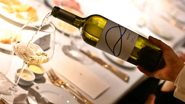 Foto colorida de homem servindo vinho