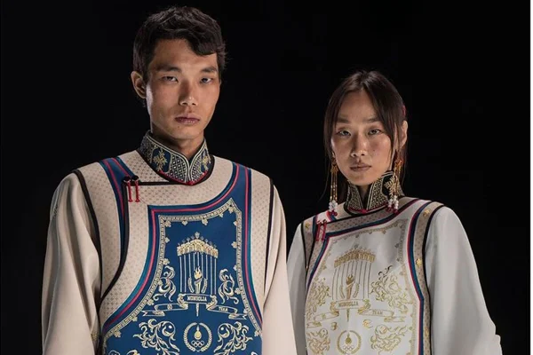 Homem e mulher posa para a foto. O homem veste um colete azul com bordado dourado e vermelho. A mulher veste o mesmo colete porém com na cor branca.