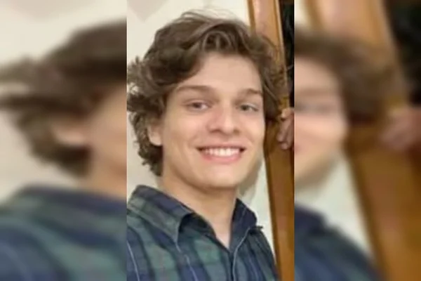 Menino branco com camisa quadriculada e sorrindo