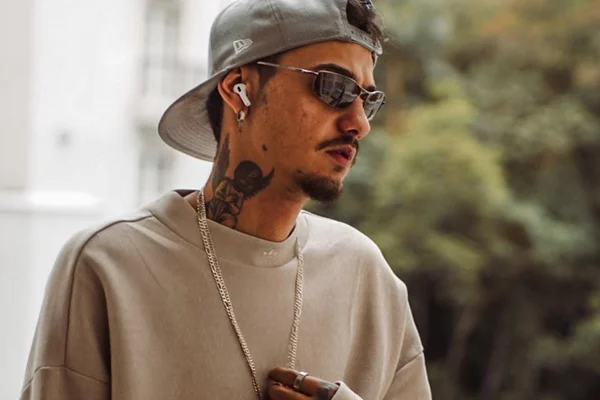 Derick Silverio, o SilverCop, posa de boné, óculos escuros e fones de ouvido - Metrópoles