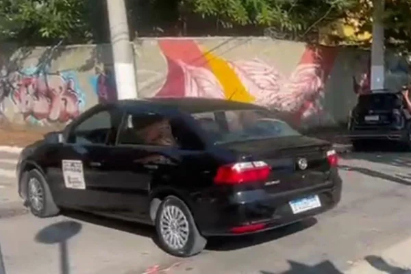Imagem colorida mostra carro preto saindo de delegacia com a psiquiatra Natalia Schincariol, ex-nora de Lula - Metrópoles