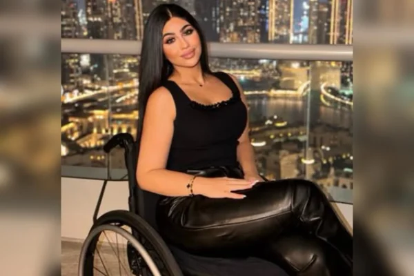 Foto colorida de mulher vestida de preto, sentado numa cadeira de rodas - Metrópoles.
