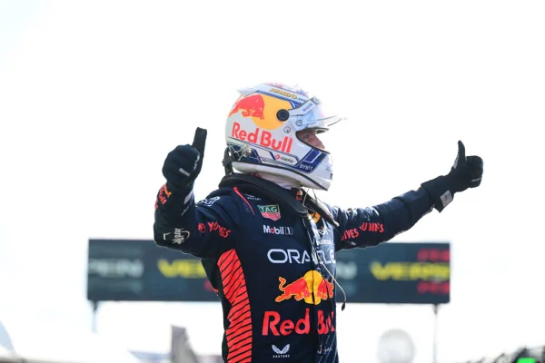 Imagem de Verstappen com os braços abertos em fundo branco - Metrópoles