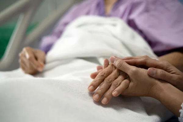cuidadora de mãos dadas com idosa hospital