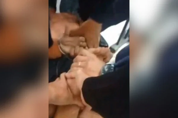 Imagem colorida mostra mãos de guardas municipais de Sorocaba algemando homem que invadiu e vandalizou creche - Metrópoles