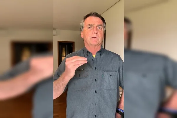 Bolsonaro, presidente e candidato à presidência, gesticula enquanto fala em vídeo sobre salário mínimo. Ele usa camisa cinza - Metrópoles
