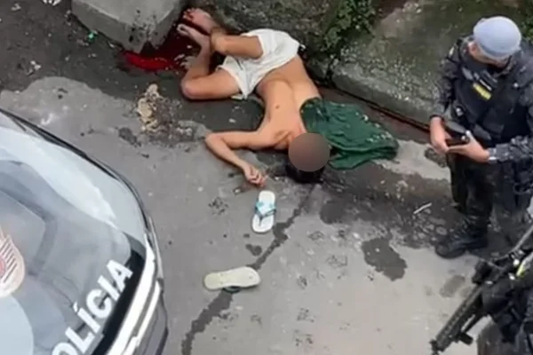 Imagem mostra policial militar (PM) ao lado de homem baleado - Metrópoles