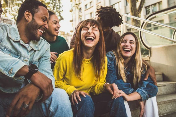 Amigos sorrindo sentados em uma calçada / escada