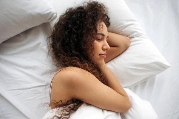 Foto colorida de mulher deitada em cama - Metrópoles