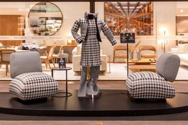 Manequim em meio a poltronas, de mesma estampa xadrez. Peças de Weider Silveiro e Ximenes Leite Arquitetura, na exposição