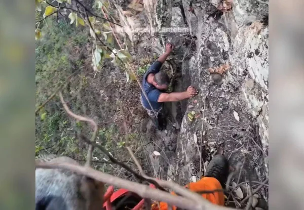 homem sendo resgatado de penhasco