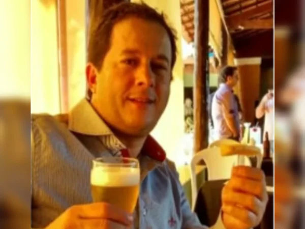 Imagem colorida do empresário Paulo José Peres, um homem branco, de camisa social segurando copo de cerveja e petisco - Metrópoles