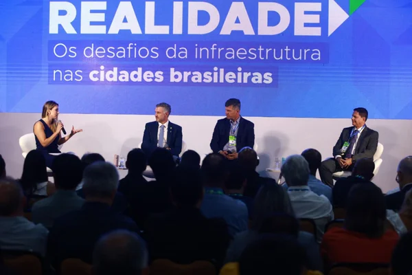 Fotografia colorida mostranbdo três homens e uma mulher em painel de live-Metrópoles