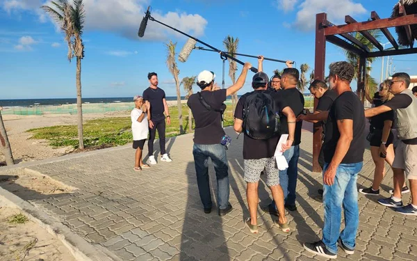 Foto colorida de gravação externa sendo feita por equipe de filmagem