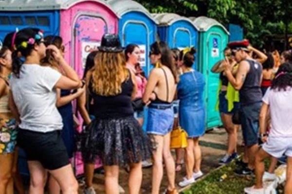 Pessoas amontoadas em frente ao banheiro público
