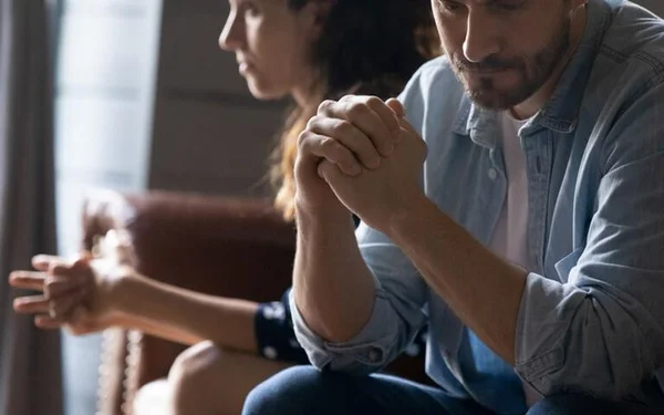 Na foto, um homem e uma mulher sentados com expressões de raiva, como se estivessem brigados