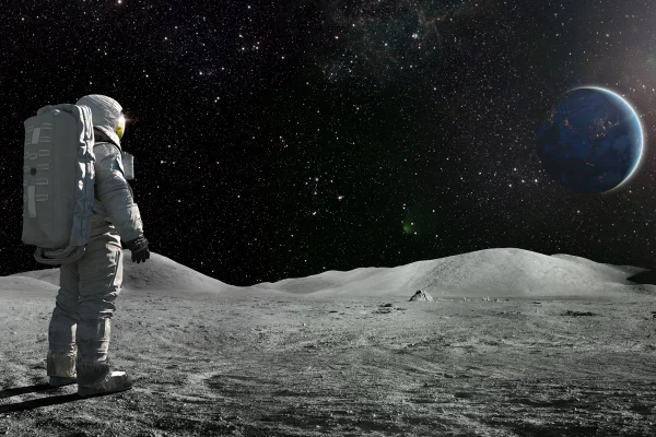Um astronauta solitário, de costas para a câmera, vestido com traje espacial completo e mochila, observa o distante planeta Terra. O sol ilumina um lado da Terra e centenas de estrelas são visíveis no espaço profundo. Metrópoles