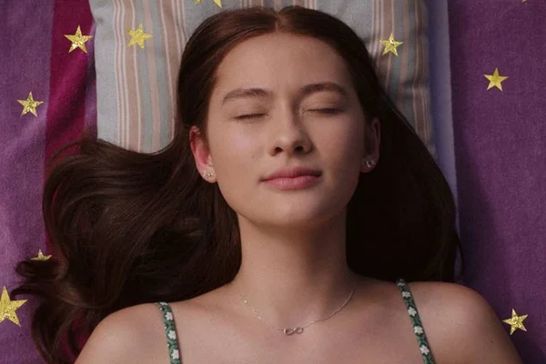 Imagem colorida de uma jovem deitada com os olhos fechados. Cena da série O Verão que Mudou Minha Vida, da Prime Video - Metrópoles