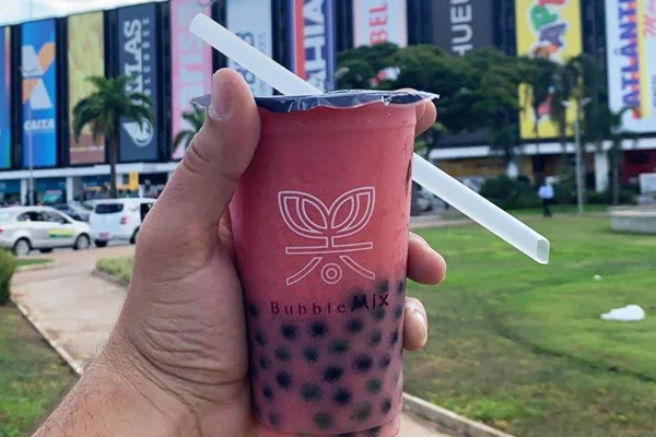 Copo com chá de bolinhas em frente à fachada do conjunto nacional