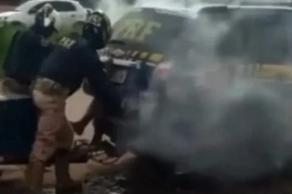 Policiais rodoviarios federais fechando porta de viatura com homem dentro. Há gás saindo do veiculo - Metrópoles