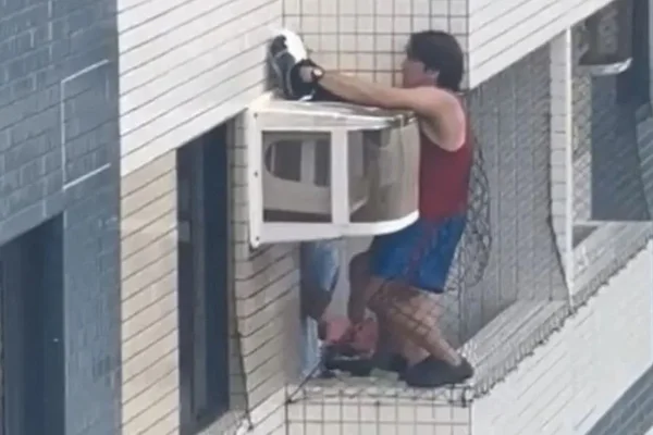 homem se pendura na varanda para resgatar gata