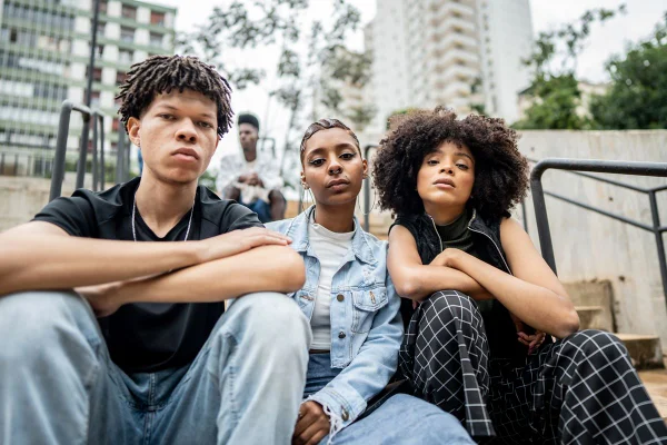 Imagem em cor, três adolescentes sentados na escada .millennials gen z- Metrópoles