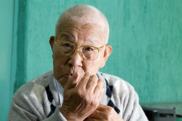 imagem colorida mostra homem de cabelos brancos. ele usa óculos e é japonês.