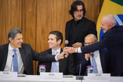 Fernando Haddad cumprimenta Lula observado por Hugo Motta