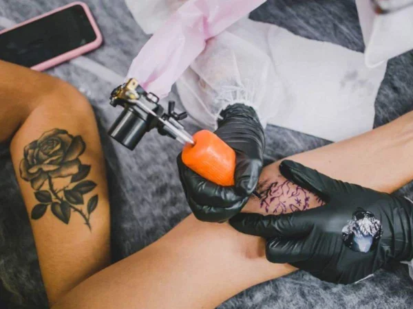 Foto colorida de pessoa sendo tatuada no braço - Metrópoles