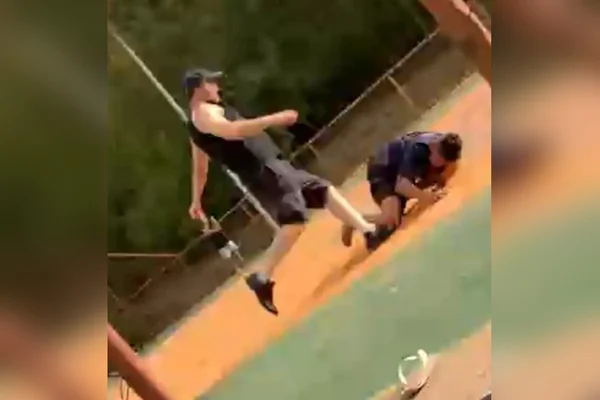 homem chutando garoto caído