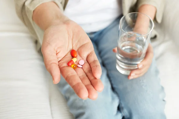 Pílulas, comprimidos, vitaminas e drogas amontoam-se em mãos maduras, vista aproximada. Harvard, pílula contra envelhecimento