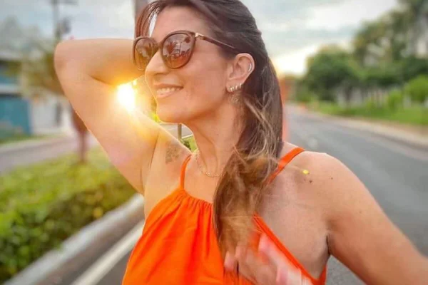 Imagem colorida de Roberta Correa. Ela é uma mulher branca e de cabelos longos. Na foto, ela está de lado, com óculos escuros, e uma mão na cabeça - Metrópoles