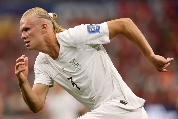 Foto colorida de homem com o uniforme da Seleção da Noruega correndo - Metrópoles