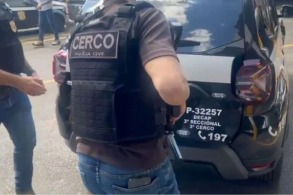 Imagem colorida mostra policiais em volta de carro - Metrópoles