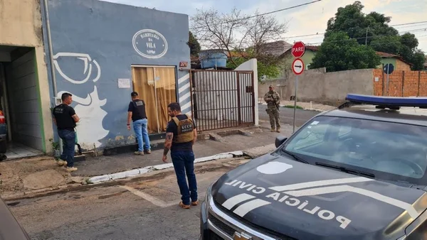 Polícia Civil do Mato Grosso faz operação em rua onde criminosos vendiam droga por delivery. Na foto agentes e um carro da polícia estão parados numa esquema, frente a uma barbearia - Metrópoles