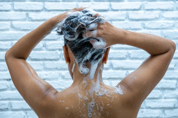 Foto colorida de uma mulher lavando o cabelo - Metrópoles