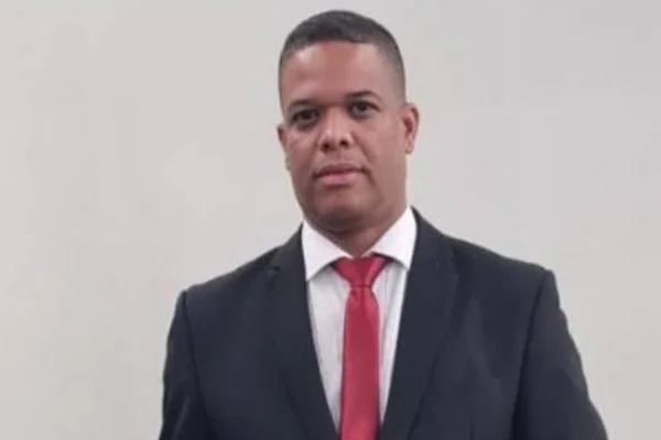 Homem de terno preto, camisa branca e gravata vermelha