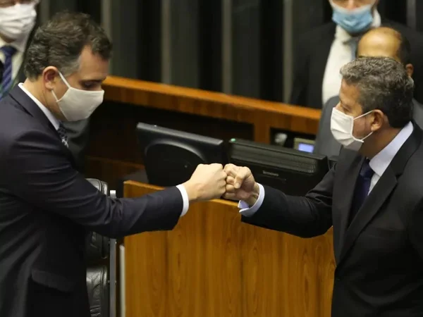 Os presidentes do Senado, Rodrigo Pacheco, e Câmara, Arthur Lira, se cumprimentam no plenário da casa legislativa. Ambos usam máscara e tocam os punhos - Metrópoles