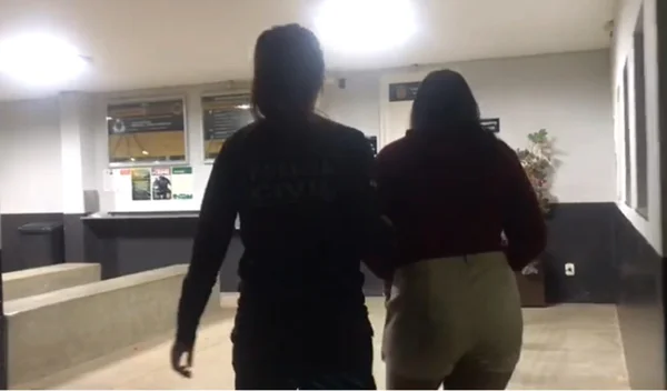 Foto colorida de mulher sendo presa por vender vaga na fila do Cras