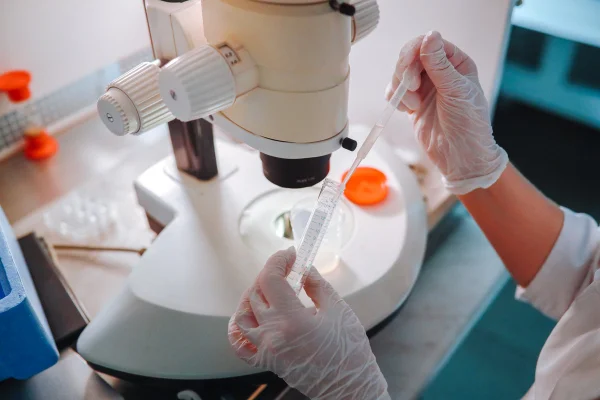 Imagem colorida mostra mão de pessoa com luva transparente testando amostra em laboratório - Metrópoles