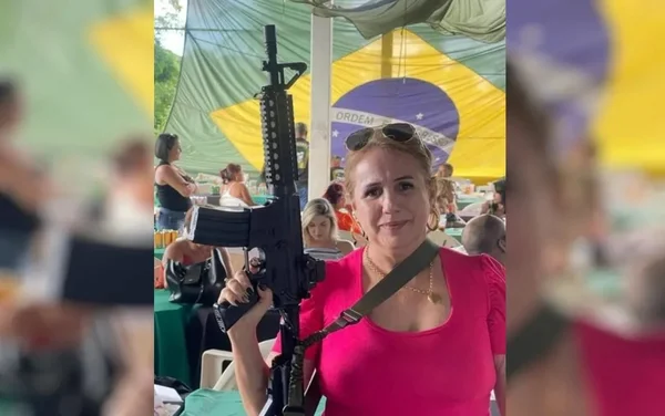 Diretora e professor de escola de Goiás empunha fuzil, sorrindo para foto. Ela é loira e usa roupa rosa, e ao fundo se vê outras mulheres e bandeira do Brasil gigante - Metrópoles